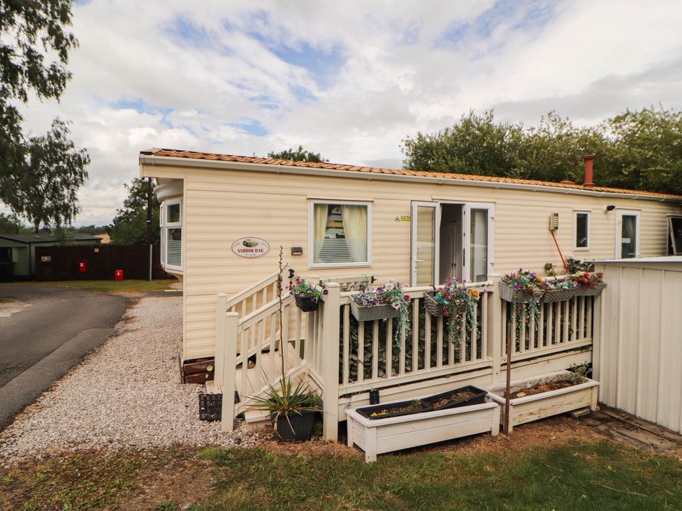 A mobile home with a deck and planters at Summer Breeze, Clitheroe