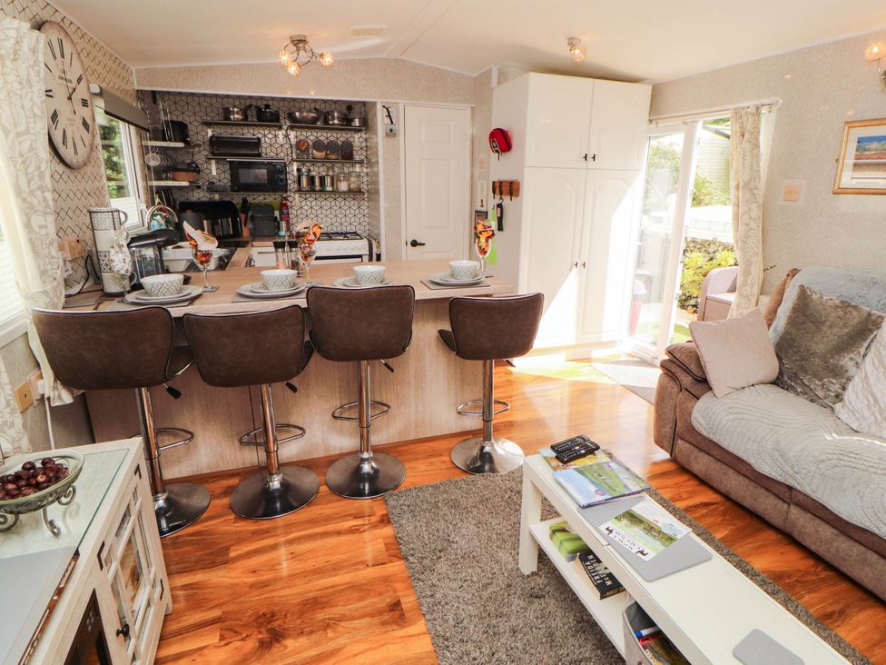 A living room with kitchen counter and bar stools at Summer Breeze in Clitheroe
