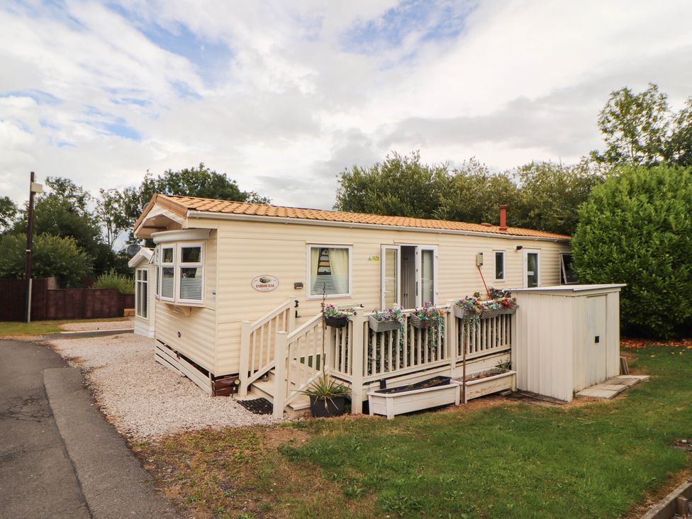 A mobile home with a deck and planters at Summer Breeze in Clitheroe