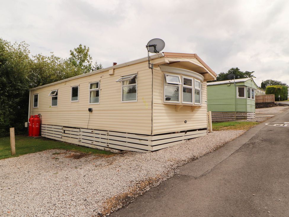 A mobile home with gas containers and a satellite dish at Summer Breeze in Clitheroe