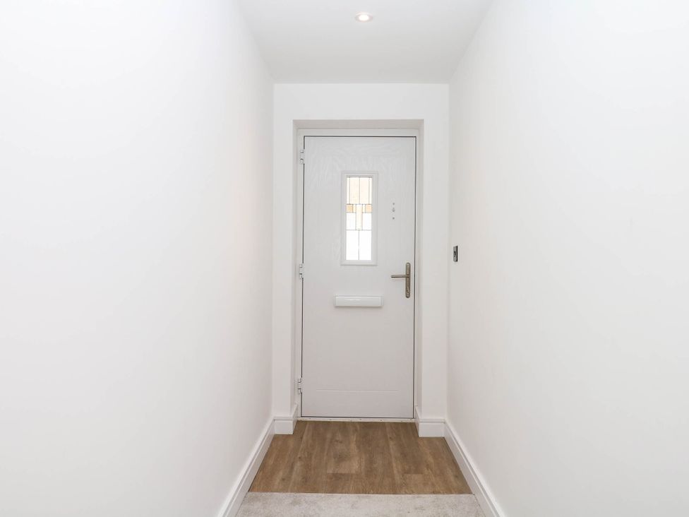A hallway with a front door and light fixture at Greenswood Mews in Brixham