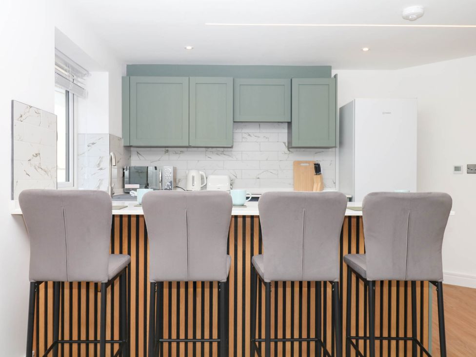 A kitchen with bar stools and appliances at Greenswood Mews in Brixham