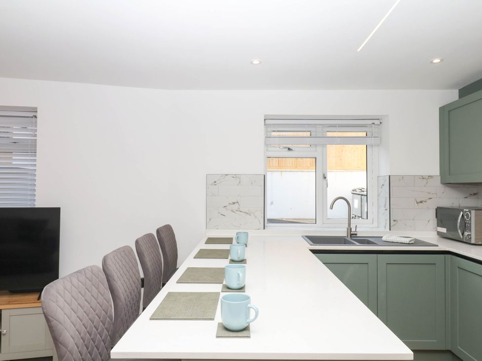 A kitchen with a sink and chairs at Greenswood Mews in Brixham