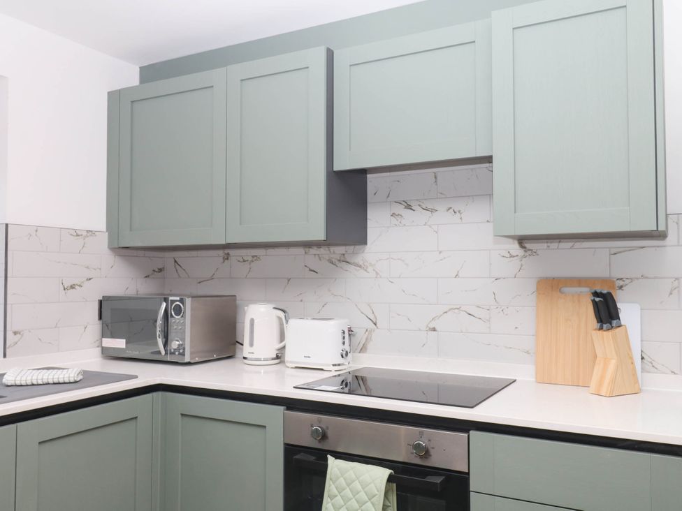 A kitchen with cabinets, microwave, kettle, and a knife block at Greenswood Mews in Brixham