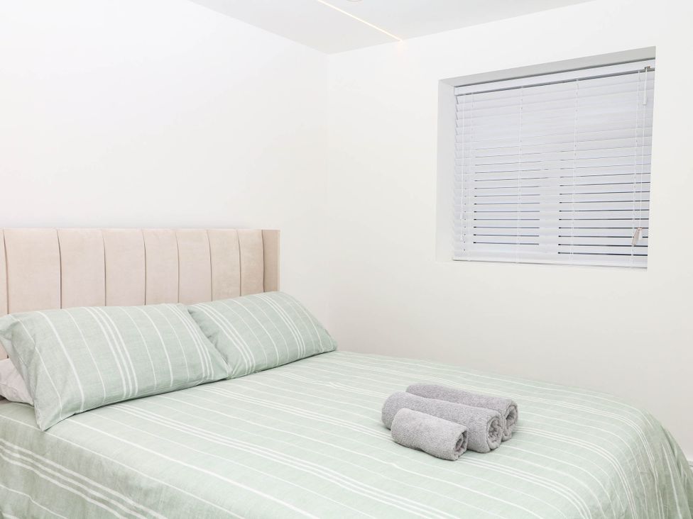A bedroom with a bed and towels at Greenswood Mews in Brixham