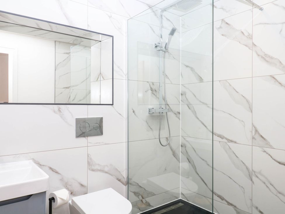 A bathroom featuring a shower, toilet, and sink at Greenswood Mews in Brixham