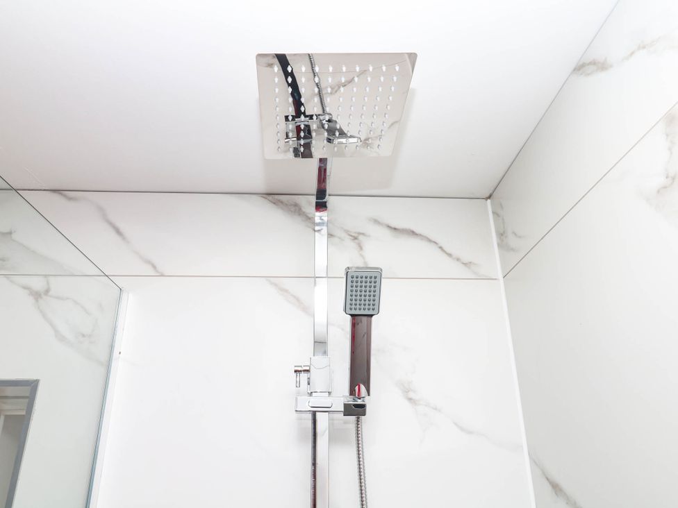 A shower head and handle in a modern bathroom at Greenswood Mews in Brixham