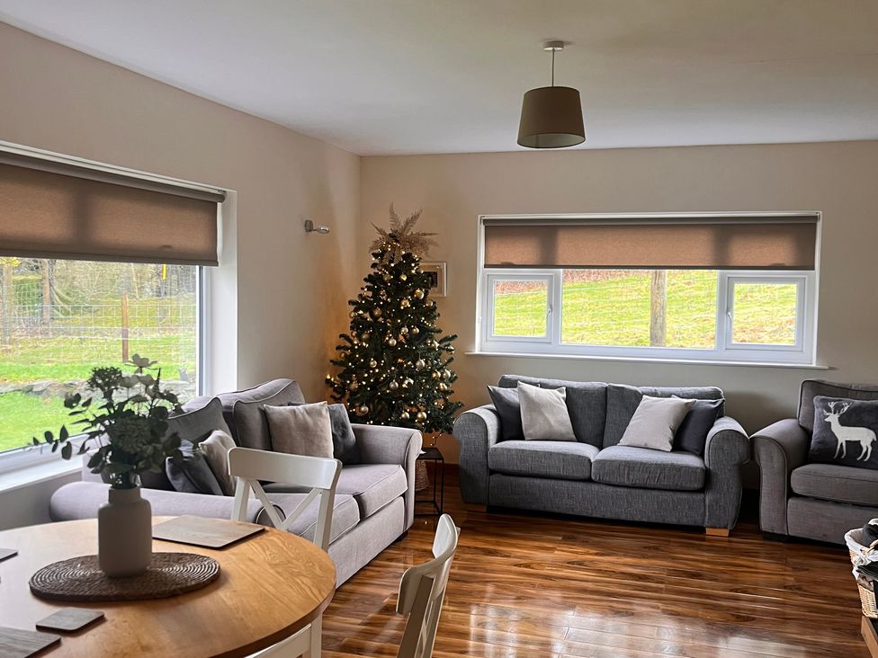 A living room with a Christmas tree and seating at Saddleback Bungalow Llandrindod Wells
