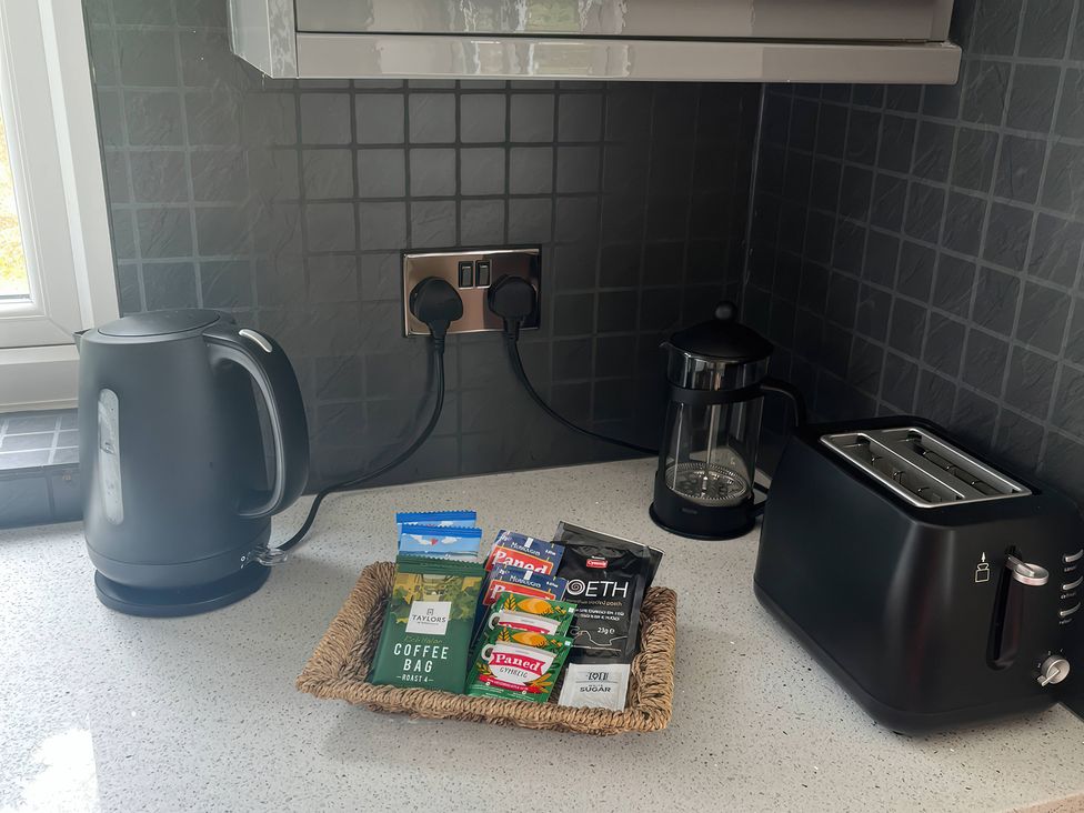 A kitchen counter with kettle, toaster, coffee, and tea bags at Saddleback Bungalow in Llandrindod Wells