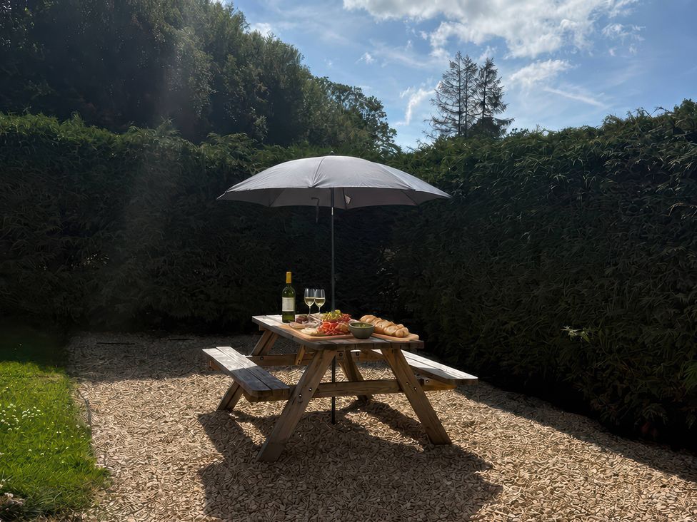A garden with a table under an umbrella at Saddleback Bungalow Llandrindod Wells