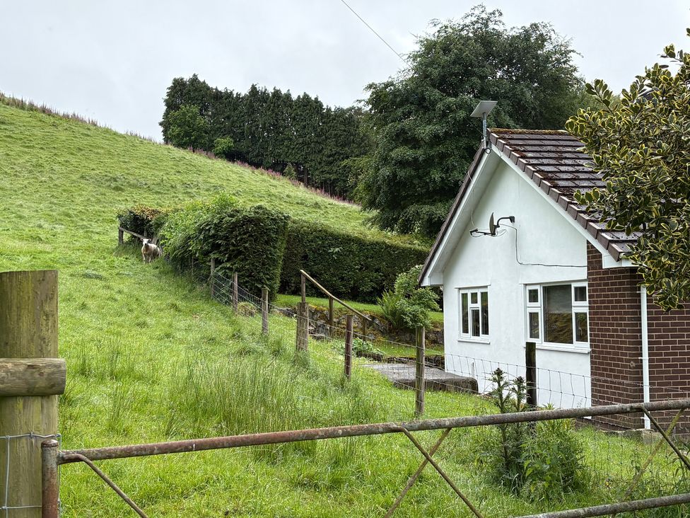 A house with a fence and grass in a rural area at Saddleback Bungalow Llandrindod Wells