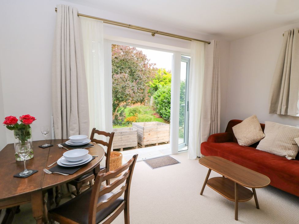 A living room with dining table and garden view at Kingswick Lodge Naphill