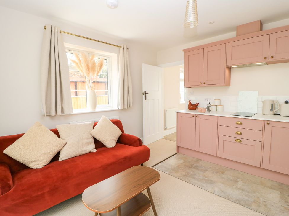 A living room with a sofa and kitchen cabinets at Kingswick Lodge in Naphill