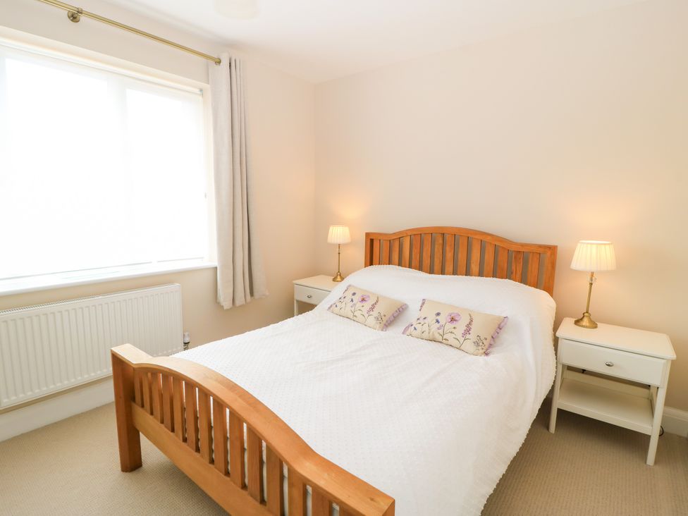A bedroom with a bed, nightstand, lamp, and window at Kingswick Lodge Naphill