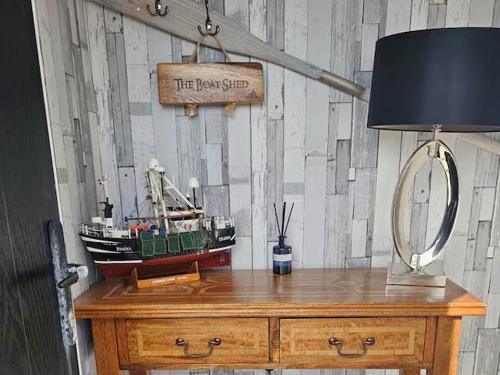 An entryway with a wooden table and a model ship at The Boat Shed in Cruden Bay