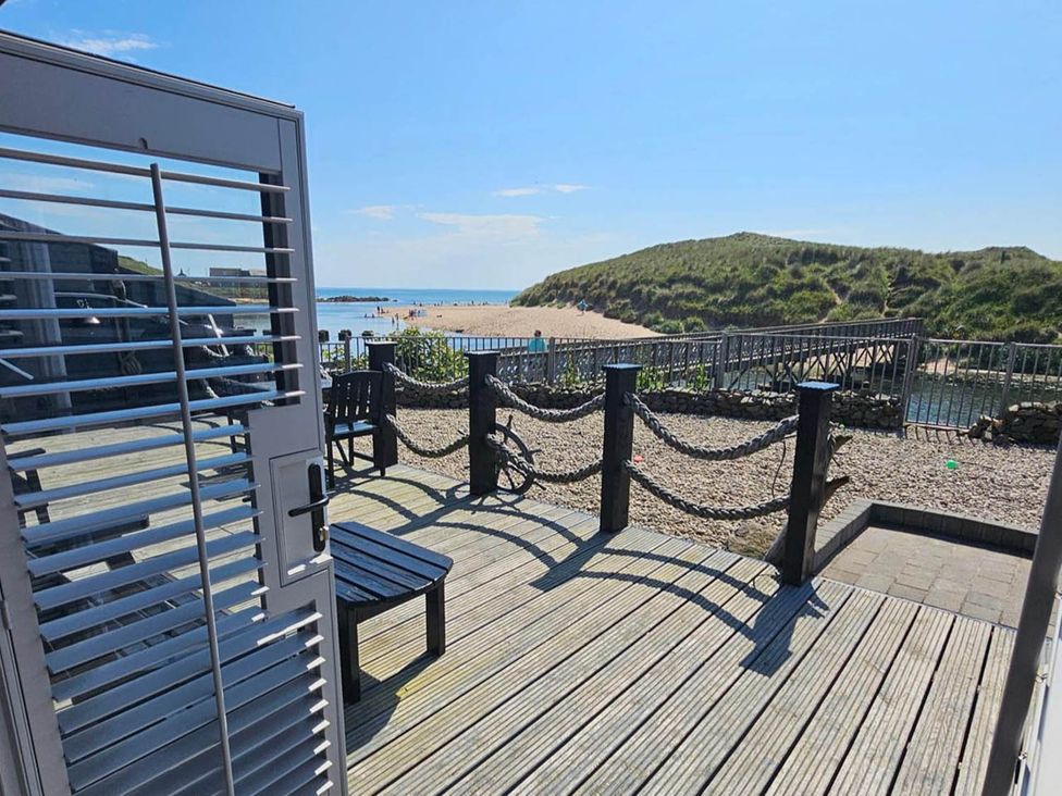 A deck area with chairs and a view of the beach and sea at 2 Bed Cottage Sleeps 4 Harbour Sea View Cruden Bay
