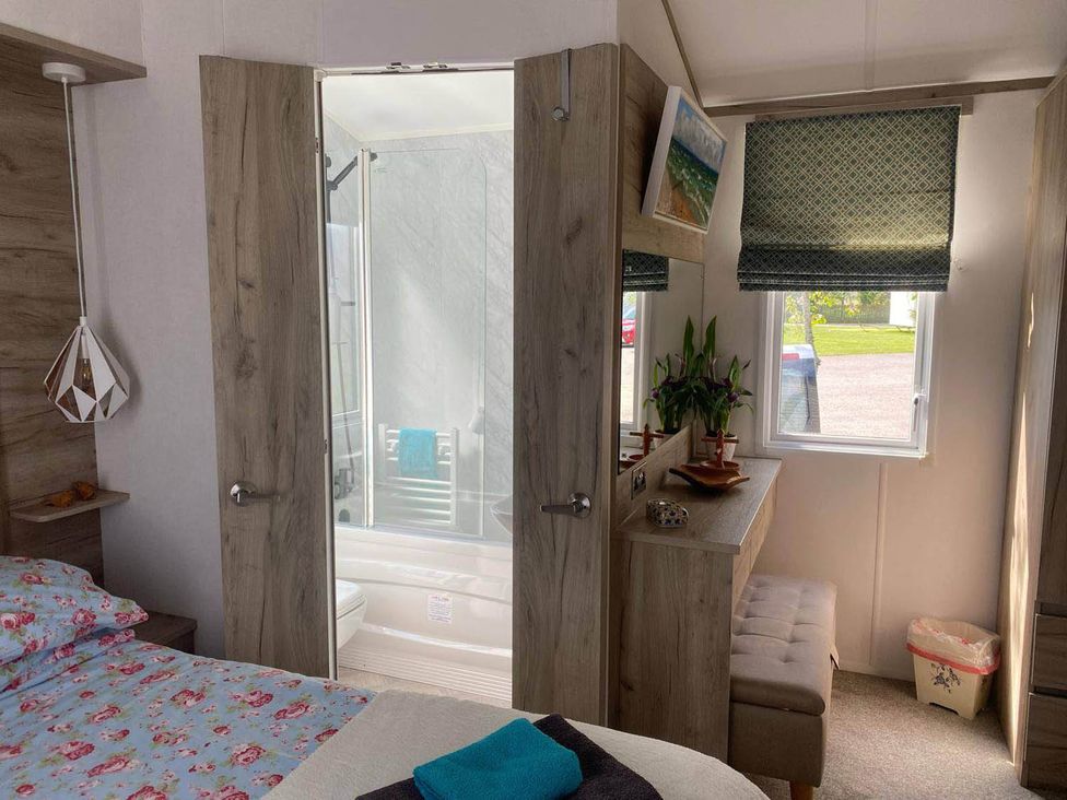 A bedroom with a bathroom entrance and a storage unit at Findhorn Lodge Peaceful Sleeps 4 Forres