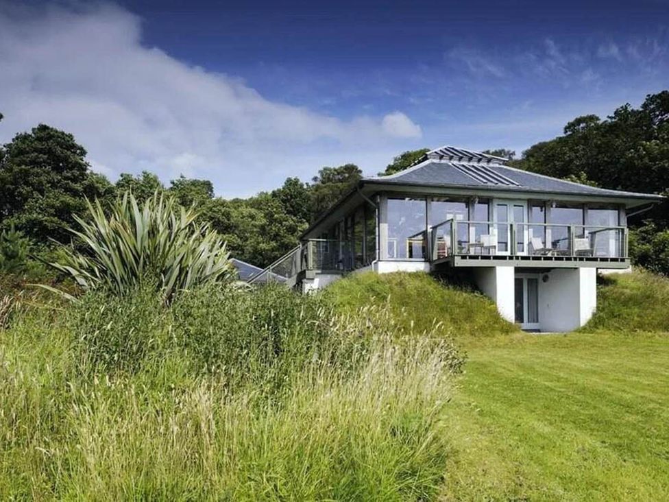 A house with a balcony surrounded by grass and trees at Tigh na Mara Sleeps 4 Sea Views Pet Friendly Drimnin near Lochaline