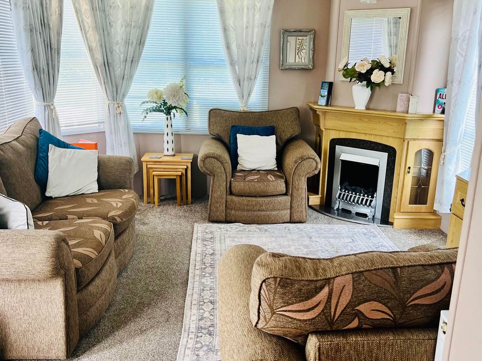 A living room with sofas, an armchair, and a fireplace at Sea Breeze A Beautiful 3 Bed Pet Friendly Retreat in Mablethorpe