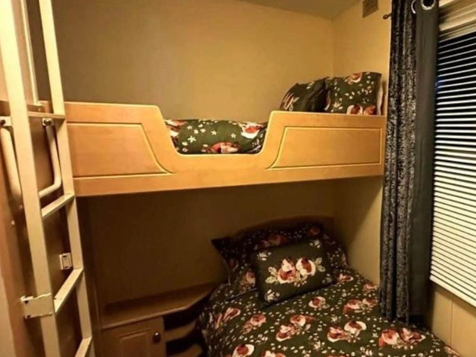 A bedroom with bunk beds and floral bedding at Sea Breeze A Beautiful 3 Bed Pet Friendly Retreat in Mablethorpe