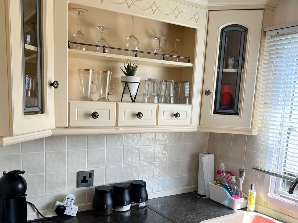 A kitchen with glassware and storage cabinets at Sea Breeze A Beautiful 3 Bed Pet Friendly Retreat, Mablethorpe