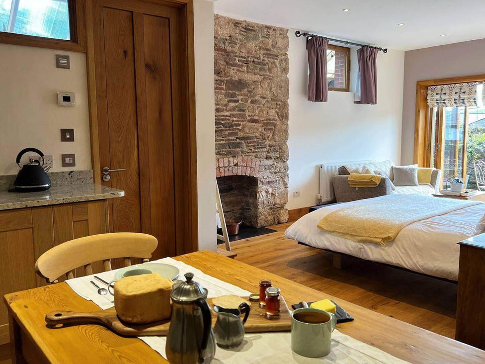 A living room with a bed, table, and kettle at Old Chapel of Ermington Converted Vestry in Ermington