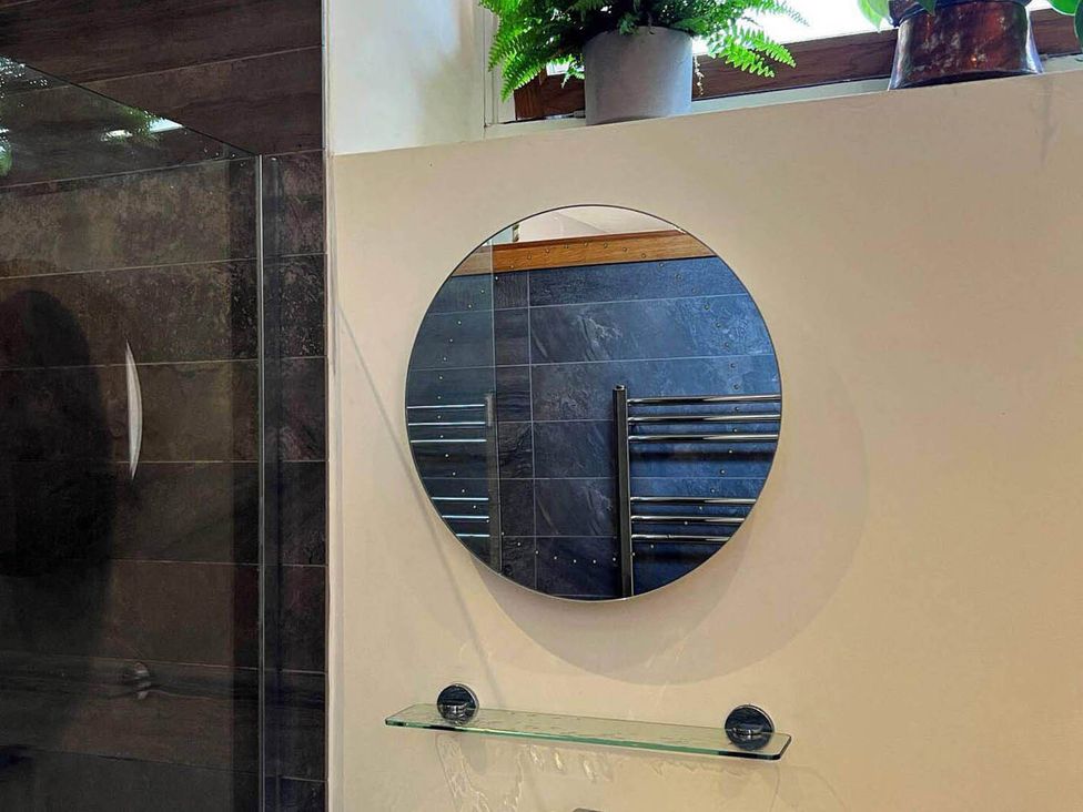 A bathroom with a round mirror and a towel warmer at Old Chapel of Ermington Converted Vestry, Ermington