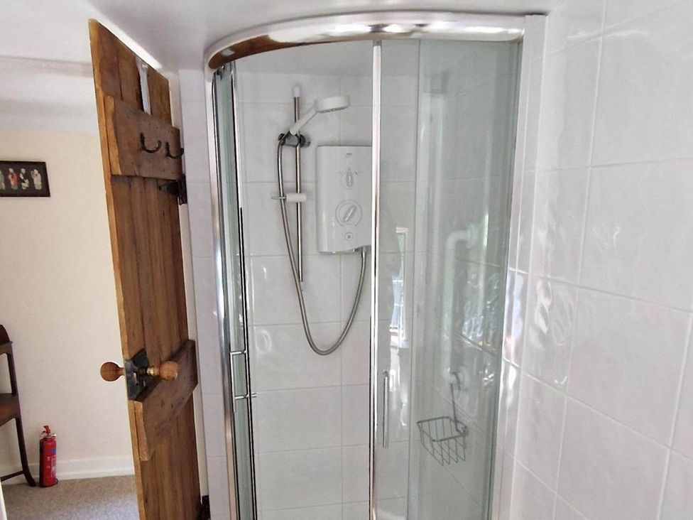 A shower with a door and controls at the bathroom