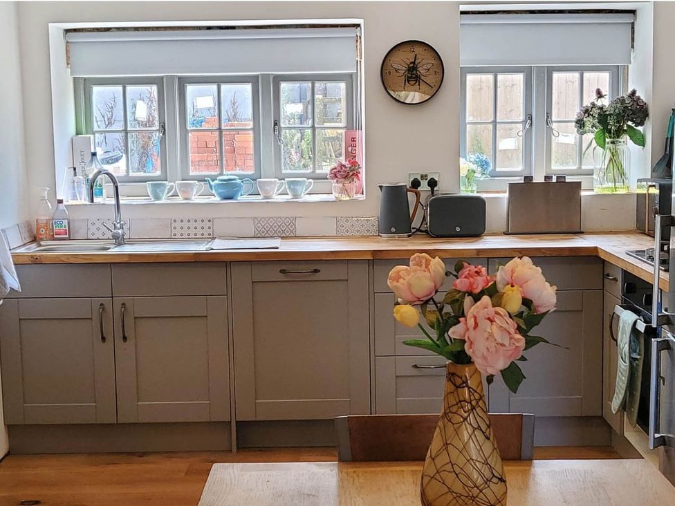 A kitchen with cabinets, sink, and flowers on the countertop at 3 Bedroom Cottage Hot Tub Garden Parking Dunkeswell