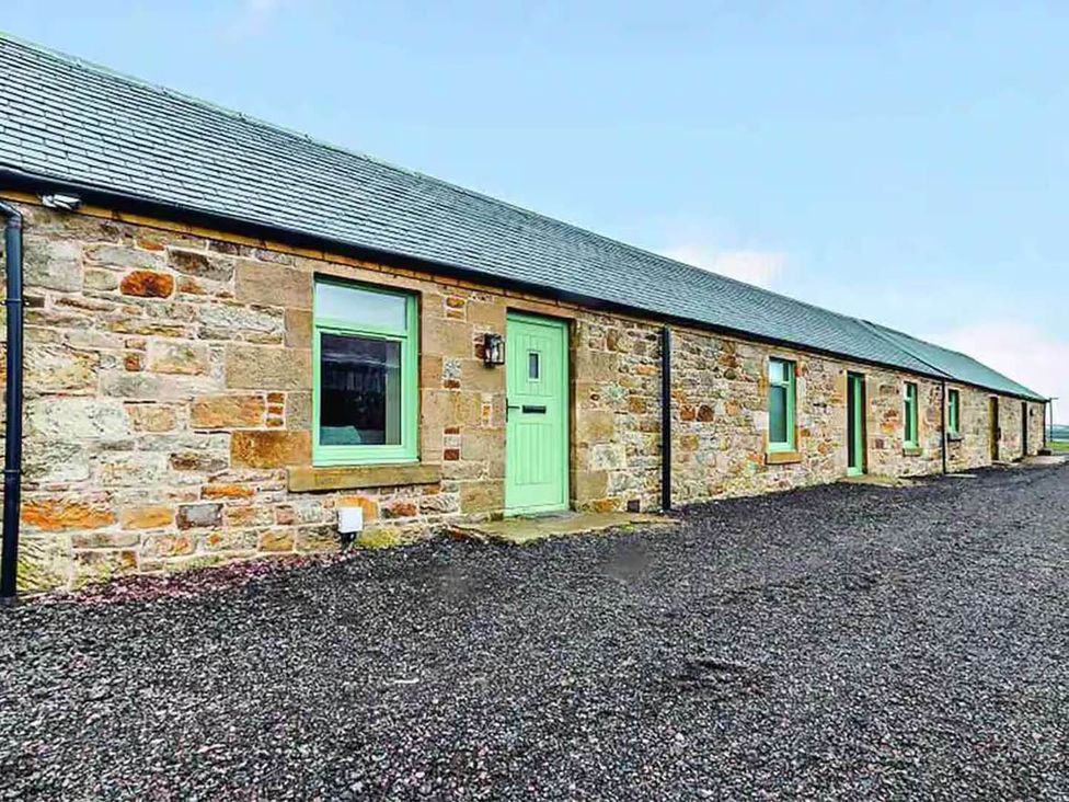 An outdoor view of a stone cottage with green windows and door at The Old Barn in Forth