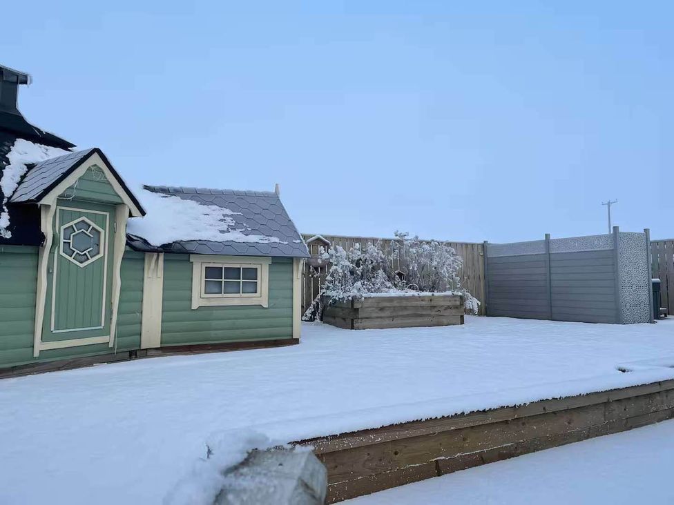 A garden with a shed and planter covered in snow at The Old Barn in Forth