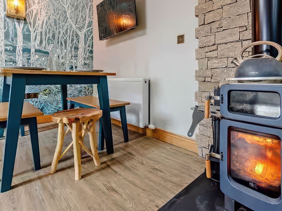 A dining room with a table and wood stove at The Old Barn in Forth