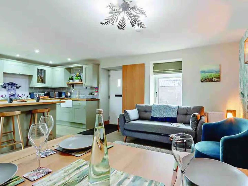 A living room with a sofa and kitchen area at The Old Barn in Forth