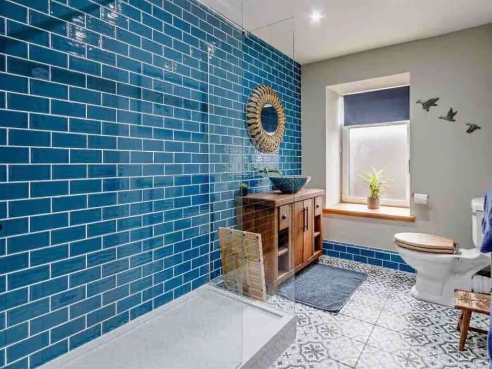A bathroom with a shower, toilet, sink, and window at The Old Barn in Forth