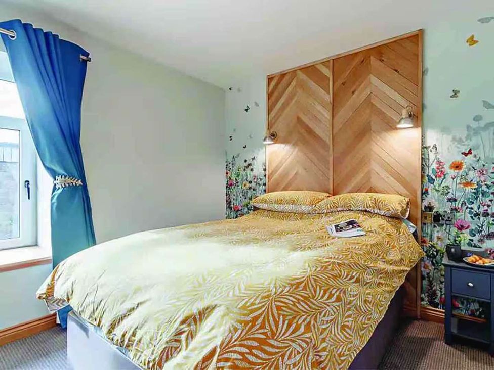 A bedroom with a bed and floral wallpaper at The Old Barn in Forth