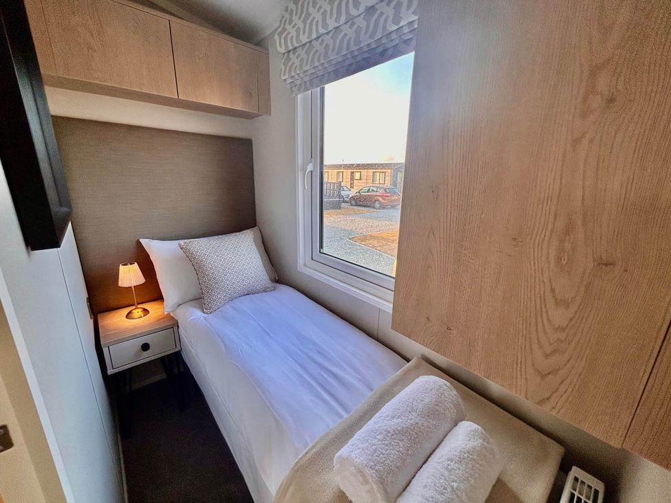 A bedroom with a single bed and bedside lamp at Lovely Holiday Home On Waxham Sands, Great Yarmouth