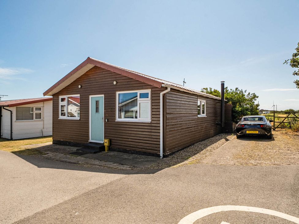 A wooden house with parked car and grass area at a property location