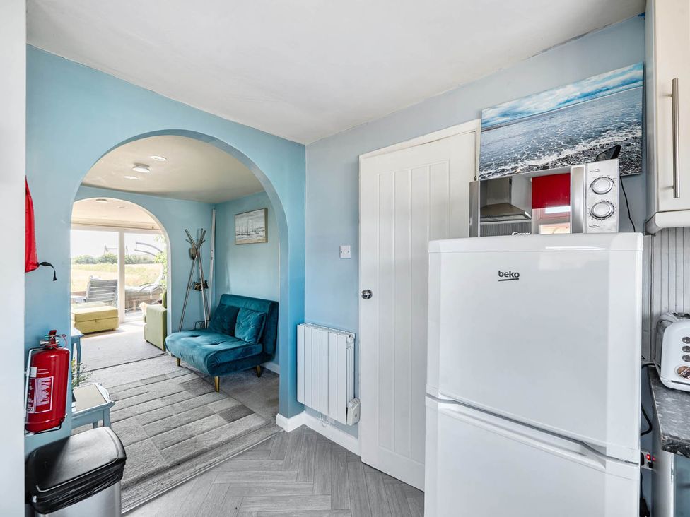 A kitchen with a fridge, microwave, and armchair at the property