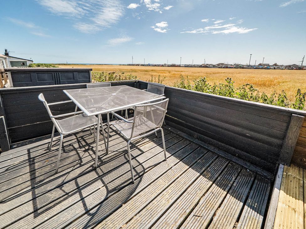 An outdoor patio with a table and chairs in a field at 