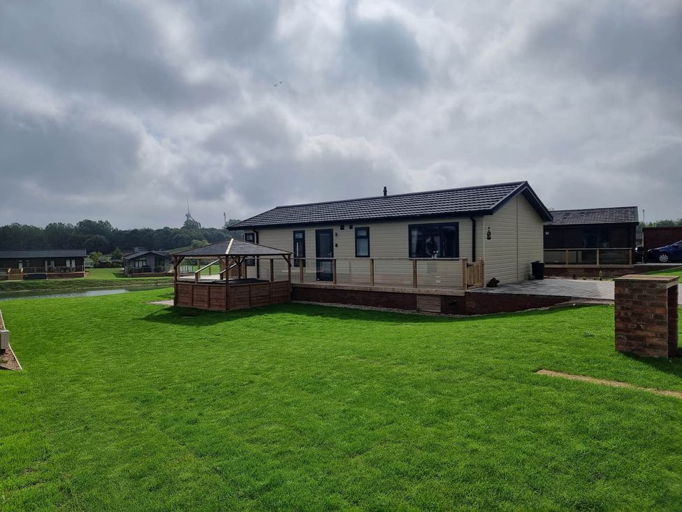 A lodge with a patio and grass area at Pet Friendly 2Bed Luxury Lodge in Routh HotTub Heron Lakes Luxury Lodge Park near Beverley