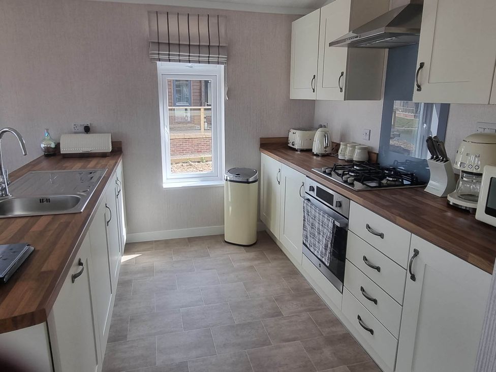 A kitchen with a sink, gas stove, and window at Pet Friendly 2Bed Luxury Lodge in Routh HotTub near Heron Lakes Luxury Lodge Park near Beverley