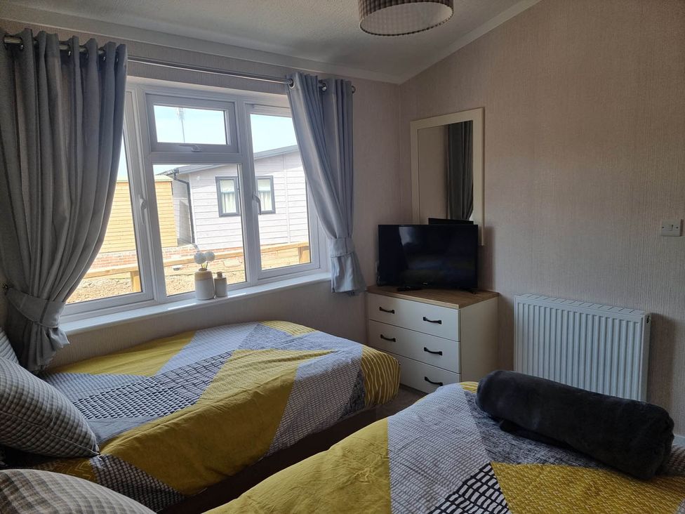 A bedroom with two beds and a television at Pet Friendly 2Bed Luxury Lodge in Routh HotTub Heron Lakes Luxury Lodge Park near Beverley