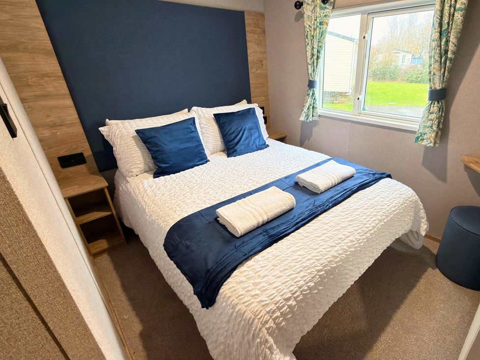 A bedroom with a double bed and window at Vintage 121 Southview Holiday Park Skegness