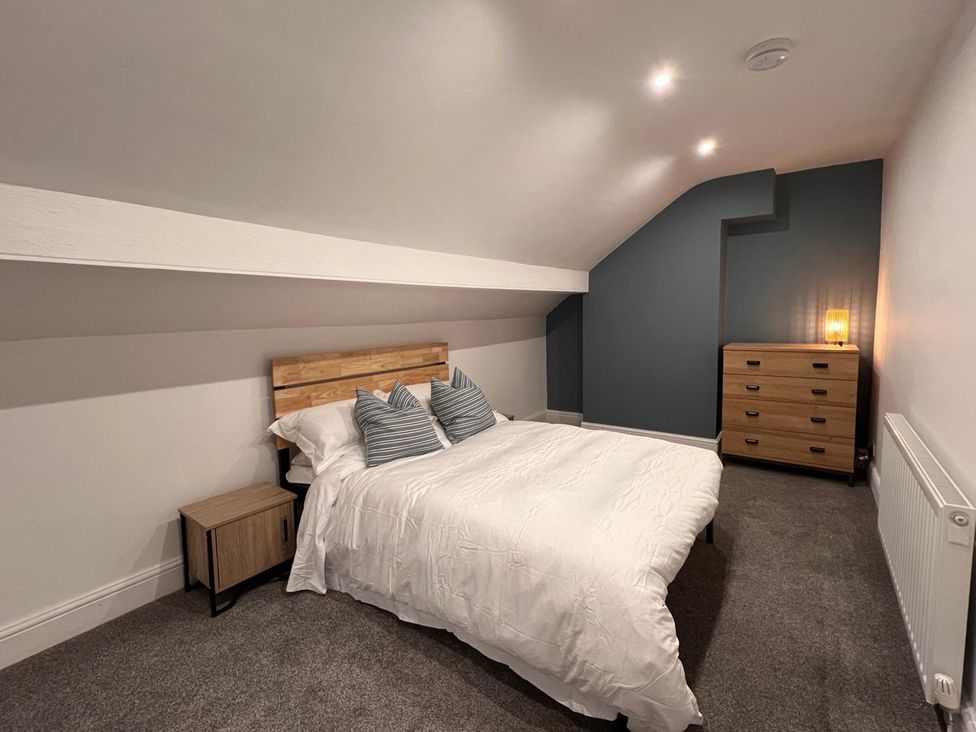 A bedroom with a bed and nightstand at 4 Bed House Sleeps 8 Garden Pets Near Beach Llandudno