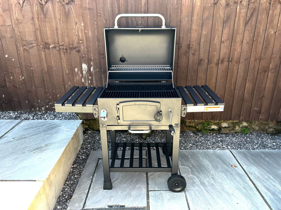 A grill with side shelves on a stone patio at 4 Bed House Sleeps 8 Garden Pets Near Beach Llandudno
