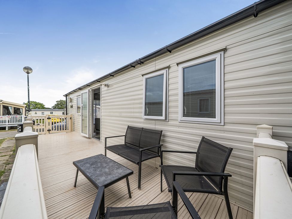 An outdoor deck with chairs and a table at Primrose Valley 3Bed Caravan Sleeps 8 Pets Ok, Primrose Valley