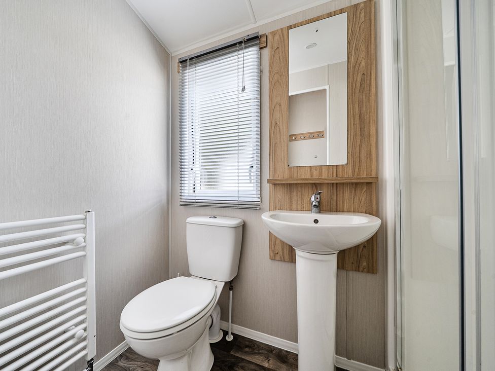 A bathroom with a toilet, sink, and mirror at Primrose Valley 3Bed Caravan Sleeps 8 Pets Ok, Primrose Valley