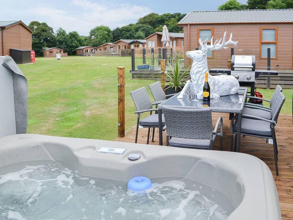 An outdoor area with a hot tub and dining table at Boutique lodge with hot tub sleeps 6 in Bridlington