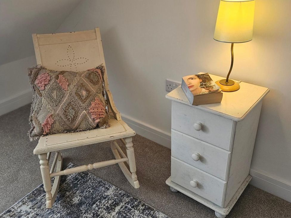 A bedroom with a rocking chair, lamp, and nightstand at 5 Bed Sleeps 7 New Build Detached Property in Monkton near Minster