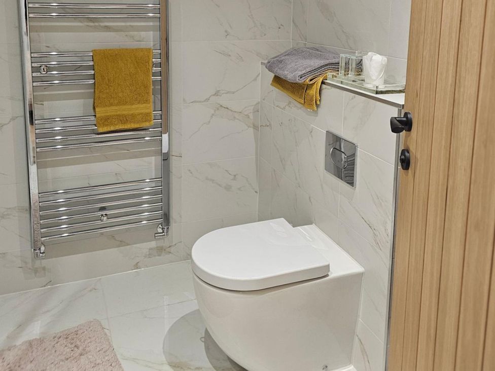 A bathroom with a toilet and towel rack at 5 Bed Sleeps 7 New Build Detached Property Monkton near Minster
